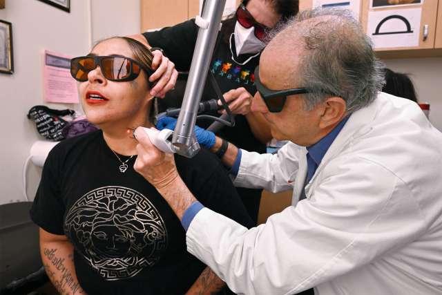 Dr. Robert Reiss removes a tattoo from Reyna Garcia at Homeboy Industries. (Photo by John McCoy | UCLA Health)