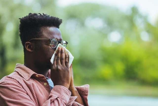 Man sneezing outside from allergy